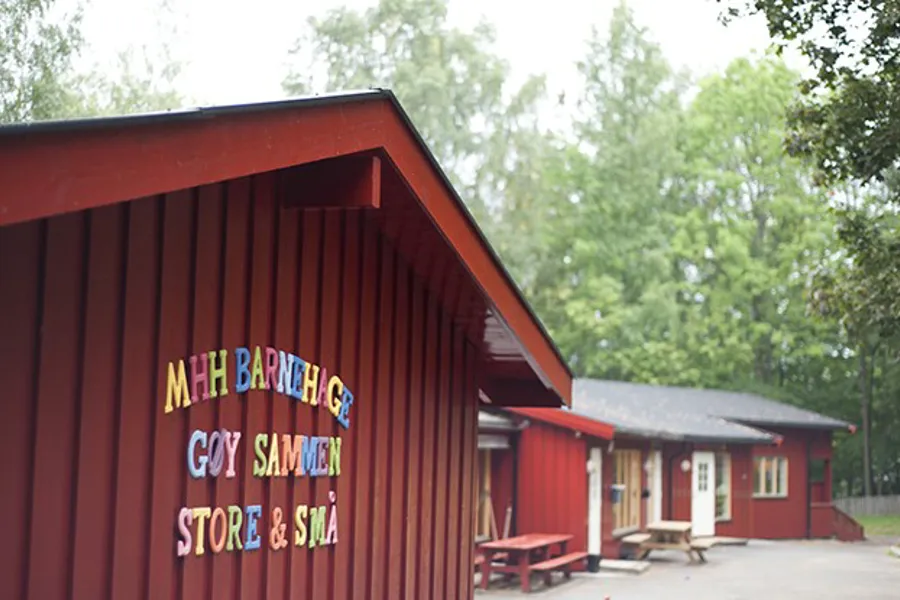 Bilde av husveggen til personalbarnehagen med skilt på veggen "MHH Barnehage Gøy sammen store og små"